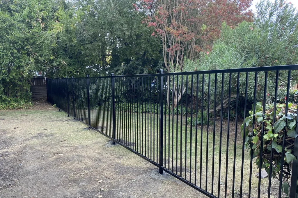 Black Iron Fence with Grass and Trees